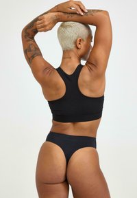Schwarzer Sport-BH mit Racerback-Design, kombiniert mit passendem hochgeschnittenem Tanga-Unterwäsche, beide mit glatter Textur.