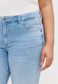 Light blue jeans made of denim, featuring a classic fit, slight fading, front pocket, and contrasting stitching along the seams.