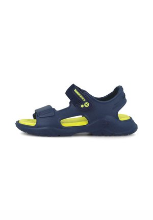 Sandares azul marino con acentos amarillos, hechos de material flexible. Cuentan con correas ajustables y un diseño abierto para mayor transpirabilidad.