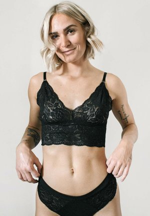 Zwarte kant bralette met bloemenpatroon, cropped ontwerp, verstelbare bandjes en bijpassende slipjes met kantafwerking, gepresenteerd tegen een neutrale achtergrond.