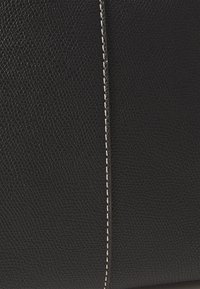 Borsa in pelle nera texture, caratterizzata da una cucitura verticale con filo bianco. La superficie presenta una finitura a ciottoli.