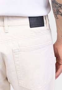 Vita jeans i denim med en figurnära design, med en svart läderlapp på baksidan, subtil sömnad och standardfickor.