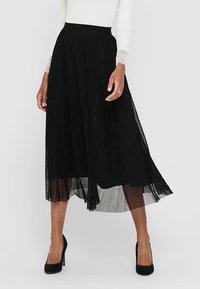 Jupe plissée noire en tissu léger, dotée d'une taille ajustée et d'une silhouette fluide qui tombe en dessous des genoux.