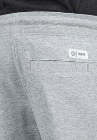 Pantalon de jogging gris clair avec une texture douce, une taille côtelée et une poche arrière avec un label logo.