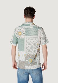 Camisa de manga corta con un diseño de patchwork en verde claro, gris y naranja. Fabricada con un tejido ligero y patrones geométricos variados.