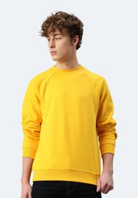 Gelbes Sweatshirt mit Rundhalsausschnitt, Raglanärmeln, gerippten Bündchen und Saum, hergestellt aus einem strukturierten Material. Figurbetonte Silhouette, lässiges Design.