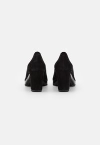Czarne zamszowe buty na wysokim obcasie z wąskim noskiem, z solidnym obcasem i gładką czarną podeszwą. Minimalistyczny design bez widocznych elementów metalowych.