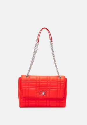 Quilted red handbag made of faux leather with silver chain strap and branded logo on the front. Rectangular shape with a flap closure.