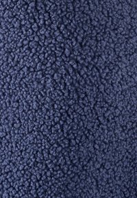 Getextureerde stof in donker marineblauw, met een pluche, donzige oppervlakte en dicht op elkaar gepakte, ronde vezels voor een zachte, tactiele ervaring.