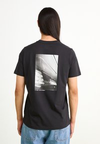 Puma AMG GRAPHIC TEE - Apdrukāts T-krekls - black