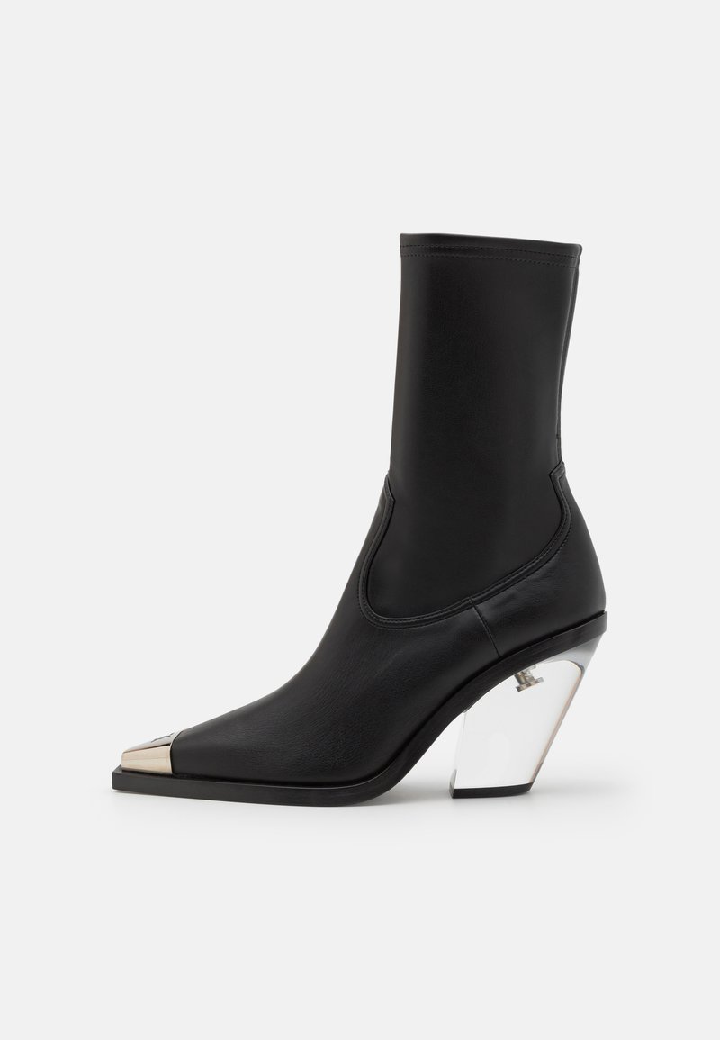 Bottine en cuir noir avec un bout pointu, un capuchon doré métallique et un talon géométrique transparent. Texture lisse, design élégant.