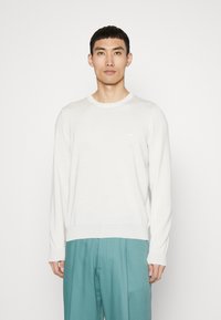 Leichter, weißer Pullover mit langen Ärmeln und geripptem Rundhalsausschnitt, ausgestattet mit dezenten Logo-Stickereien auf der Brust und einem lässigen Schnitt.