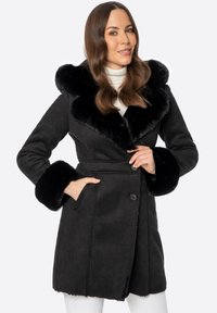 Czarny zamszowy płaszcz z puszystym czarnym kołnierzem i mankietami z futra. Posiada zapięcie na guziki i boczne kieszenie. Gładka faktura i dopasowany krój.