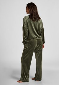 Olijfgroen velours pyjama set met een ontspannen pasvorm, voorzien van lange mouwen en losse broeken, met een zachte textuur en minimale naaddetails.