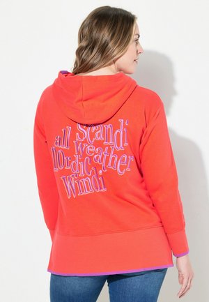 Rot kapuzensweatshirt mit lila Akzenten. Hat einen übergroßen Schnitt und auffälligen Text auf der Rückseite mit der Aufschrift "alle skandinavischen nordischen Wetter Windi."