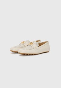 Cream loafers with textured canvas panels, gold-tone hardware detailing, and rubber soles. Low profile with rounded toes and subtle accents.