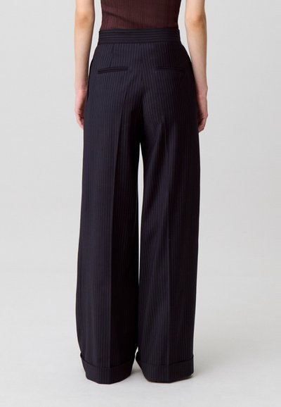 Pantaloni a gamba larga in blu navy scuro con sottili righe verticali, dotati di una vita alta e tasche posteriori, realizzati in un tessuto liscio.