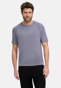 Korte mouw, ronde hals T-shirt in lichtgrijs, gemaakt van zachte stof met een gestructureerde afwerking en subtiele stikdetails. G gedragen met donkere broeken.