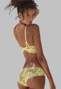 Geel kanten lingerie set met doorzichtig gaasdetail, bloemenpatronen, verstelbare bandjes en geschulpte randen. Zicht van achteren.