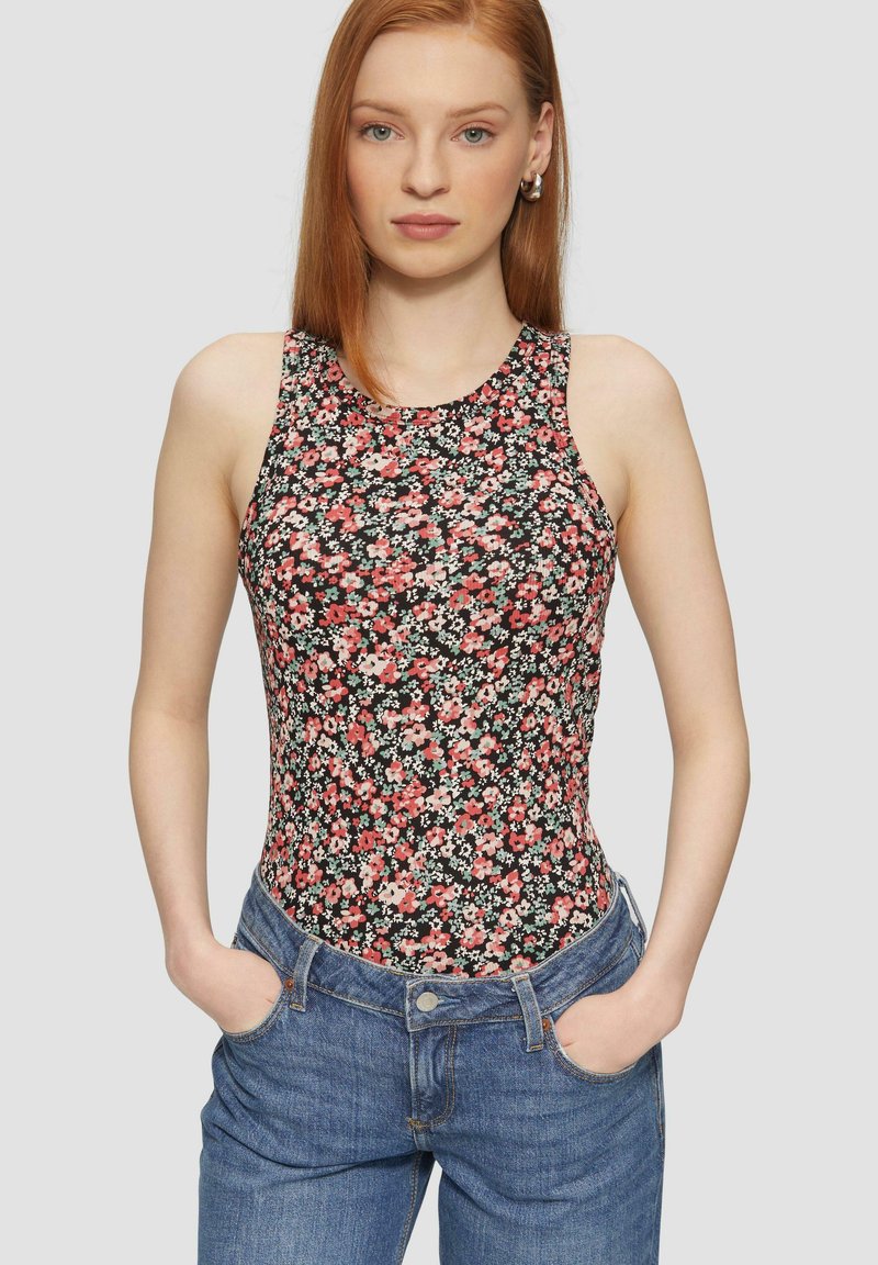 Bloemenbodysuit met een hoge hals en mouwloos ontwerp. Zwarte achtergrond met roze en witte bloemen. Gecombineerd met blauwe denim jeans.