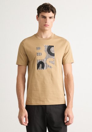 Beige bomull t-skjorte med et blokk-mønster grafikk i svart og hvitt på fronten, rund halslinning og korte ermer.