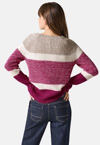 Randig tröja med horisontella band i lila, beige och kräm. Stickad struktur med rundad halsringning och ribbade ärmslut. Avslappnad passform.