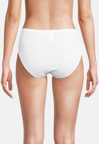 Donna che indossa semplici slip di cotone bianchi visti di spalle su uno sfondo bianco.