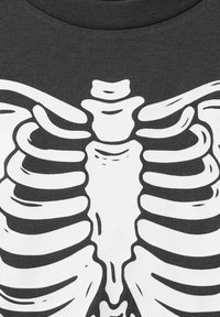 Mörkgrå t-shirt med en vit grafisk tryck av ett människobröstkorg, som visar detaljerade ben och en jämn tygtextur.