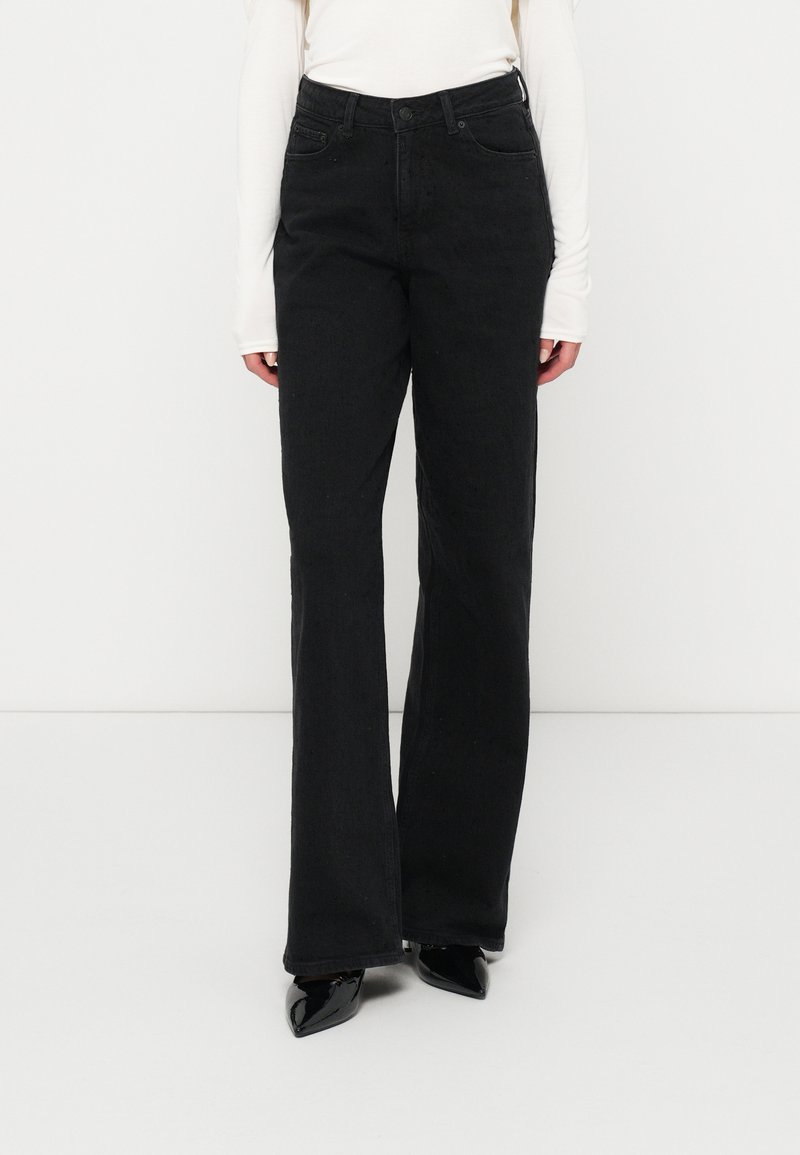 Czarne dżinsy z rozszerzanymi nogawkami i wysokim stanem, z przednimi kieszeniami oraz klasycznym zapi�ęciem na guzik. Teksturowany materiał wprowadza subtelny detal.