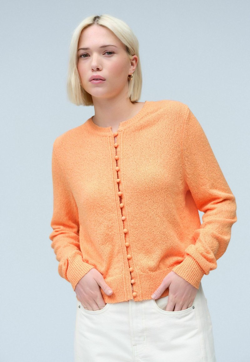 Knopfneuer Cardigan in lebhaftem Orange mit strukturiertem Stoff, runder Halsauschnitt und dekorativen Knöpfen an der Vorderseite; lange Ärmel.