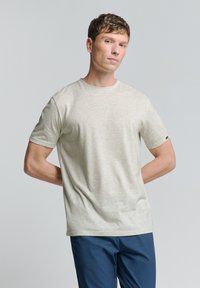 Lichtgrijze t-shirt met korte mouwen, gemaakt van zachte stof. Heeft een ronde halslijn en een subtiele textuur, met een klein logo detail op de mouw.