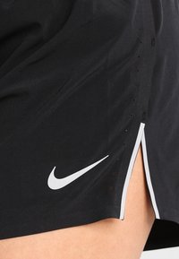 Pantalones cortos deportivos negros hechos de tejido ligero que cuentan con un logo de Nike en blanco, aberturas laterales y pequeños agujeros de ventilación para transpirabilidad.