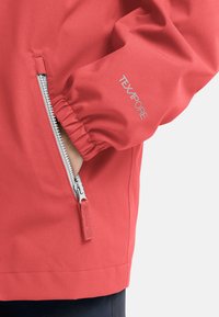 Giacca impermeabile rossa con tasca con zip, polsini elasticizzati e un'etichetta di stoffa con la scritta "TEXAPORE." Texture liscia e design leggero.