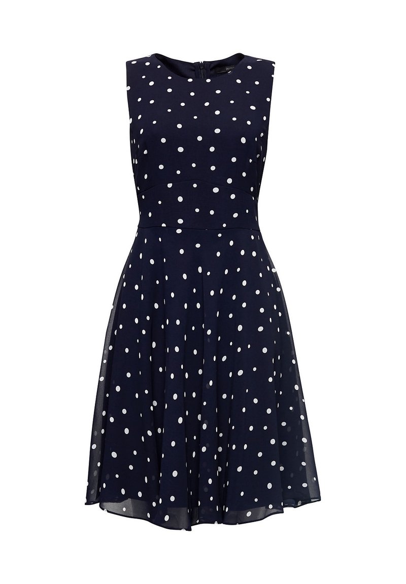 Marinblå ärmlös klänning med vita prickar, figursydd bodice och utställd kjol. Har en dold bakre dragkedja och en mjuk tygtextur.