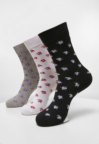 Tre par strumpor i grått, vitt och svart, med små blommönster i rosa och lila. Materialet verkar mjukt med ribbade manschetter.