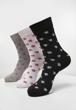 Tre par strumpor i grått, vitt och svart, med små blommönster i rosa och lila. Materialet verkar mjukt med ribbade manschetter.