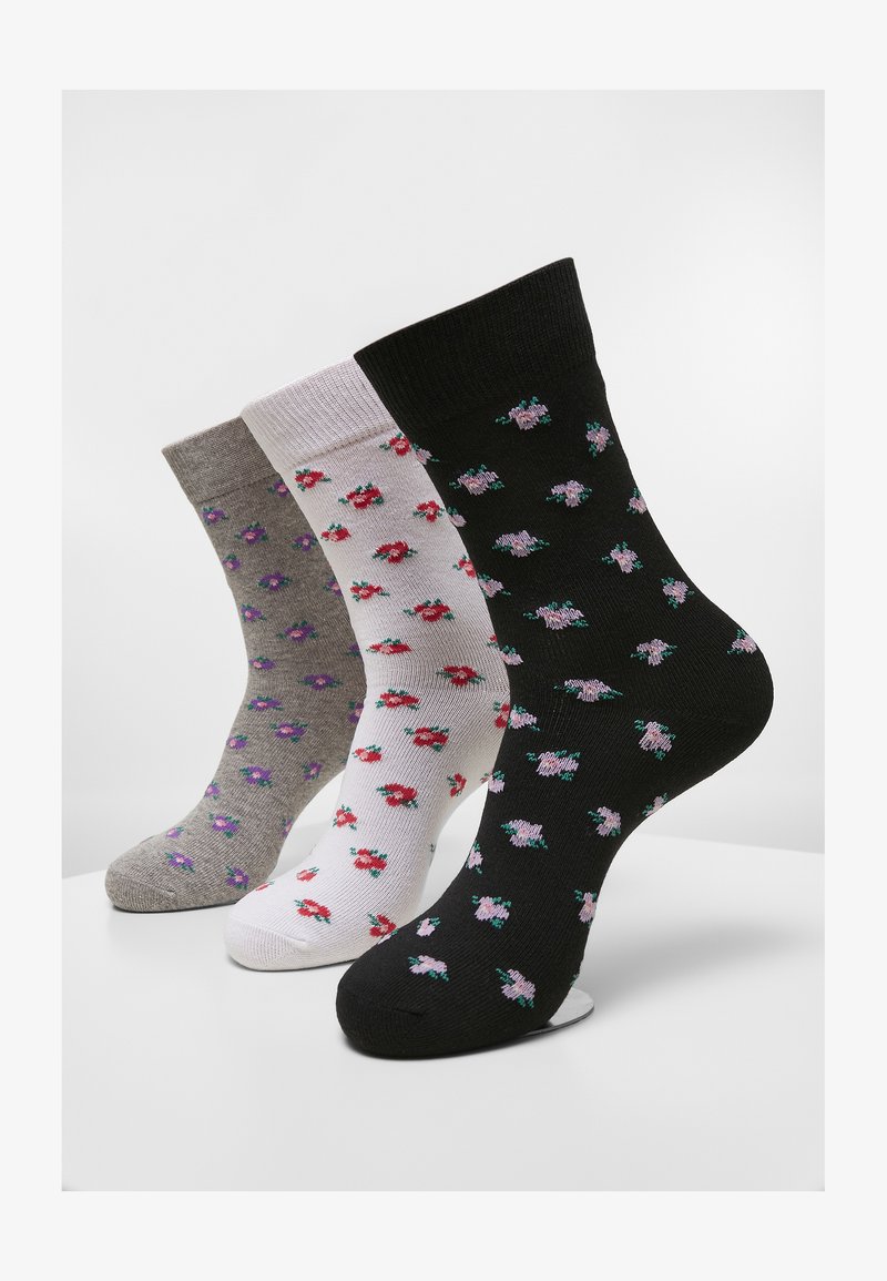 Tre par strumpor i grått, vitt och svart, med små blommönster i rosa och lila. Materialet verkar mjukt med ribbade manschetter.