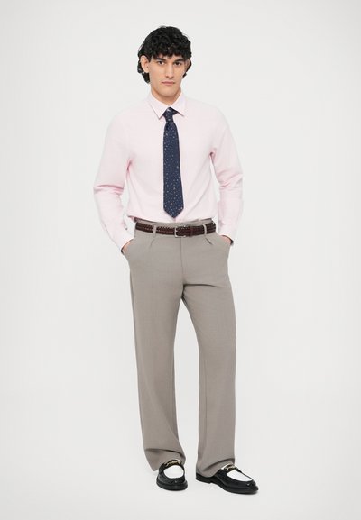 Cămașă roz deschis, cravată bleumarin cu mici stele albe, pantaloni gri cu dungi, curea maro țesută, pantofi negri cu accente albe.