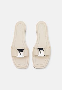 Beige slide sandals with a square shape, wide strap, silver buckle accent, and subtle stitching details on the footbed.