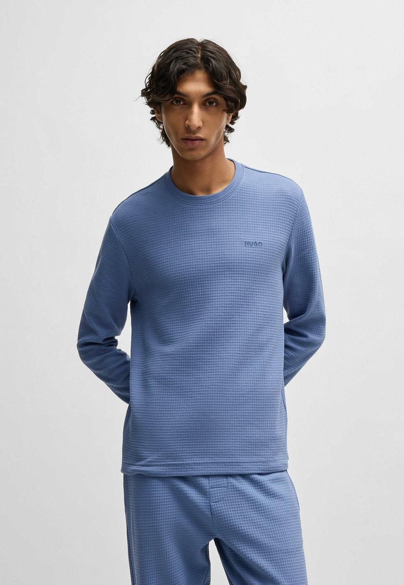 Langsleeve, wafeltextuur shirt in lichtblauw met een ronde halslijn en een klein logo op de borst.