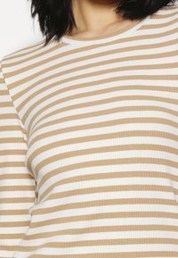Geripptes Top mit horizontalen Streifen in wechselnden Beige- und Weißtönen, mit Rundhalsausschnitt und figurnahem Schnitt.