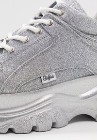 Srebrne sneakersy z brokatem na przysadzistej podeszwie, z białymi sznurówkami, metalowymi detalami i metką z logo. Teksturowana cholewka i wyściełana podeszwa środkowa.