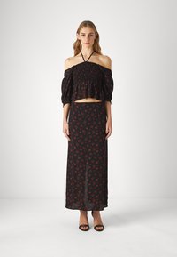 Schwarzes Blumen-Zweiteiler-Outfit mit einem gerafften Off-Shoulder-Crop-Top mit Puffärmeln und einem passenden langen Rock mit roten Mustern.