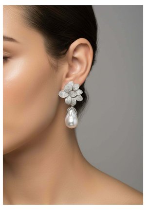 Primer plano de la oreja de una mujer que lleva un pendiente floral de diamantes con una gran perla colgante sobre un fondo neutro.