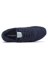 Marinblå idrottssko tillverkad av mesh och mocka, med snörning, vadderad krage och en grå gummisula med subtila varumärkesdetaljer.