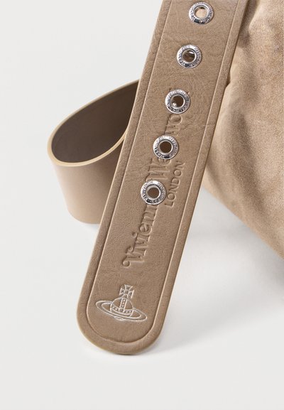 Μπεζ δερμάτινο λουράκι με μεταλλικά τελείες, ανάγλυφο κείμενο και λογότυπο "Vivienne Westwood London", προσαρτημένο σε αντικείμενο από σουέτ ύφασμα.