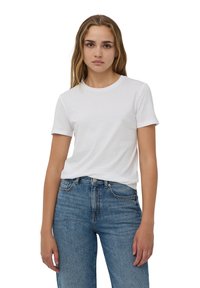 T-shirt bianca in cotone con scollatura tonda classica e maniche corte, abbinata a jeans in denim blu a vita alta con una leggera scoloritura.