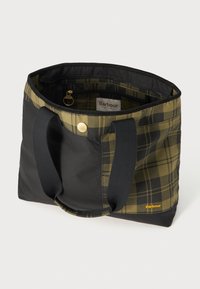 Bolsa tote em padrão xadrez preto e oliva com fecho de zip, alças largas e um detalhe em botão dourado. O interior inclui um bolso com zip e uma etiqueta com logótipo.