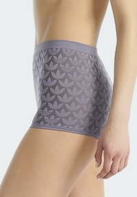 Fialové boxerské trenýrky s hladkým páskem zdobeným opakujícím se květinovým vzorem. Tkanina má jemnou, pružnou texturu.