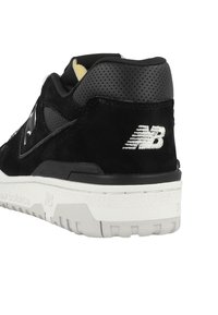 Black suede sneaker with perforated black leather accents. Features white rubber outsole and embroidered logo on the heel.